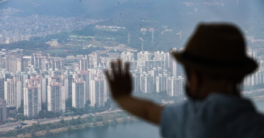 한 시민이 송파구 롯데월드타워 서울 스카이 전망대에서 아파트 밀집 지역을 바라보고 있다.<연합뉴스>